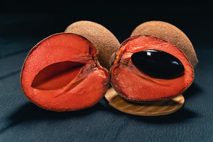 Mamey fruit cut open, showing its orange flesh and large pit